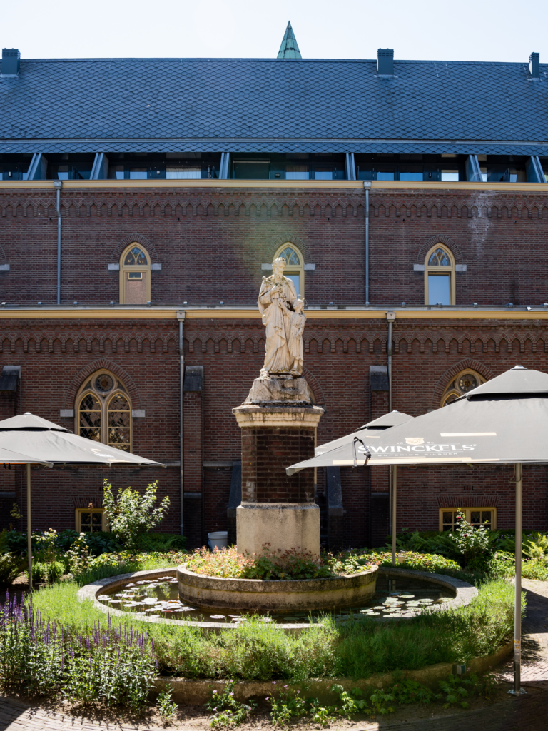 Binnentuin van Hemels met beeld, fontein en parasols, met zonnepanelen op het dak